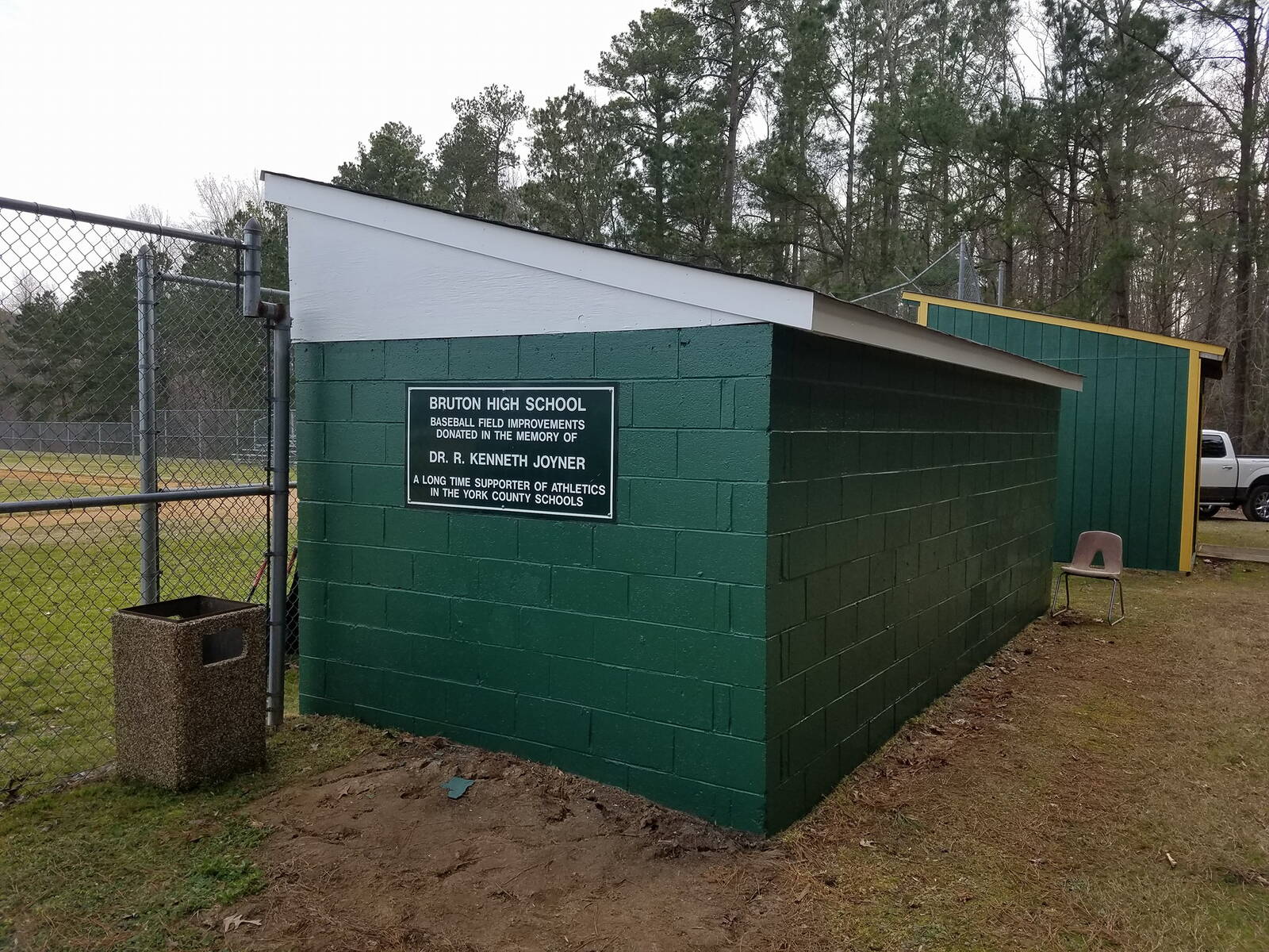 Freshly painted green outbuilding beside a fenced field