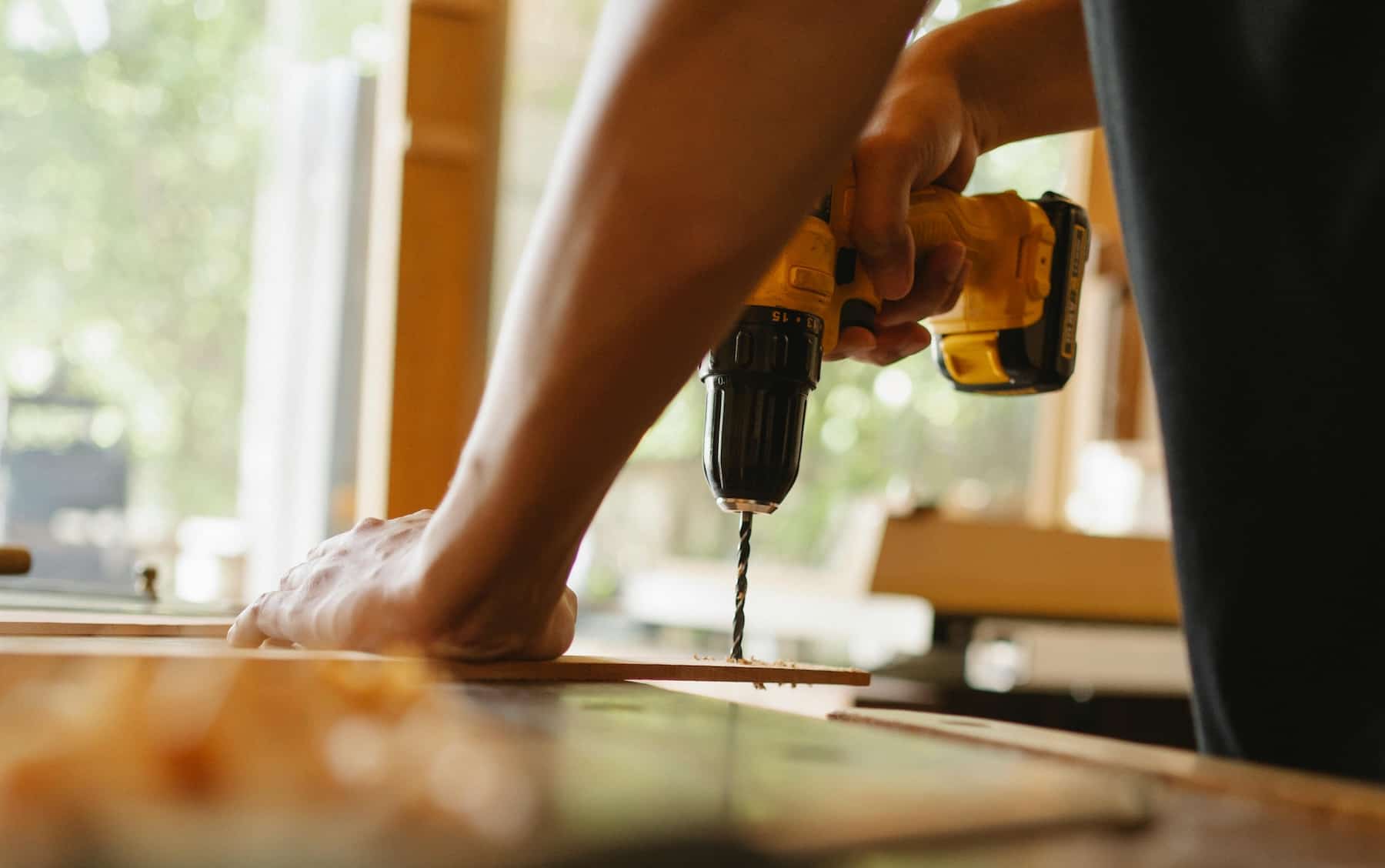 Carpenter using a cordless drill on wood trim during a home repair