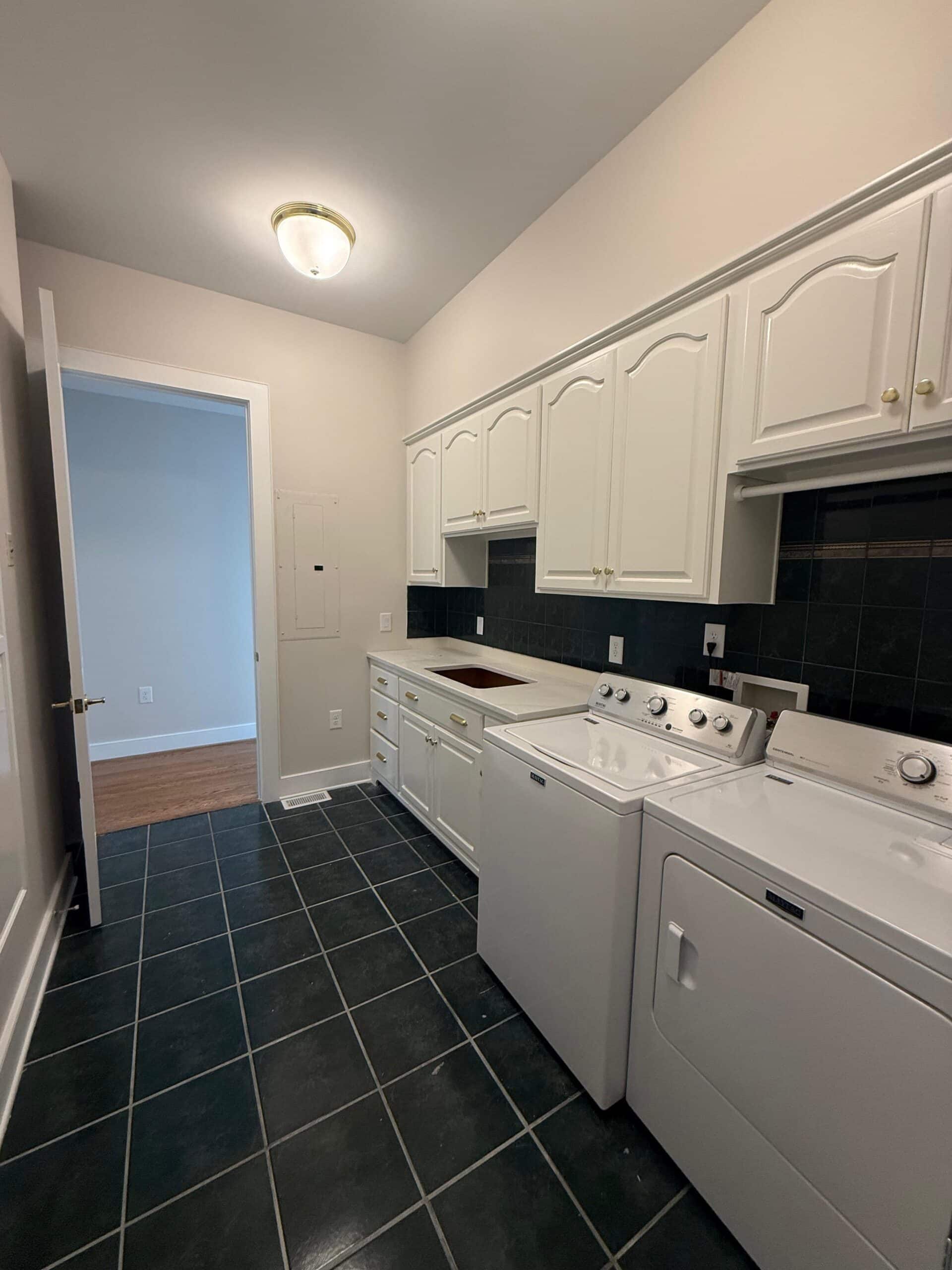 White painted cabinets in a room with dark tile flooring