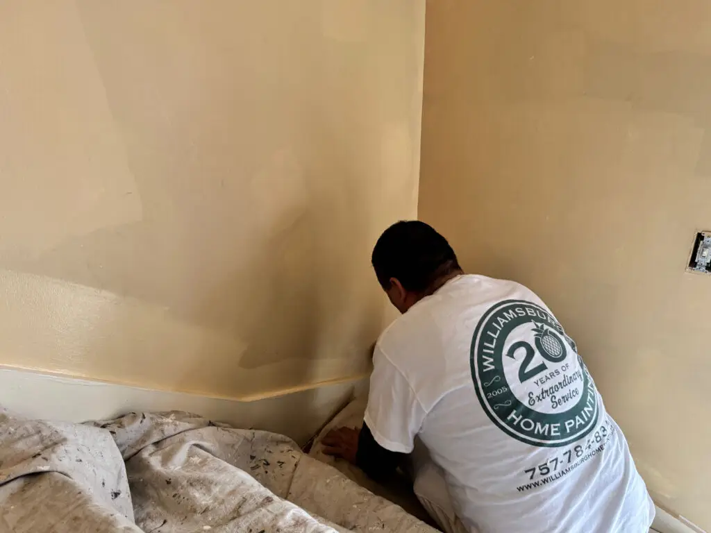 Painter smoothing joint compound on an interior wall during drywall repair before painting